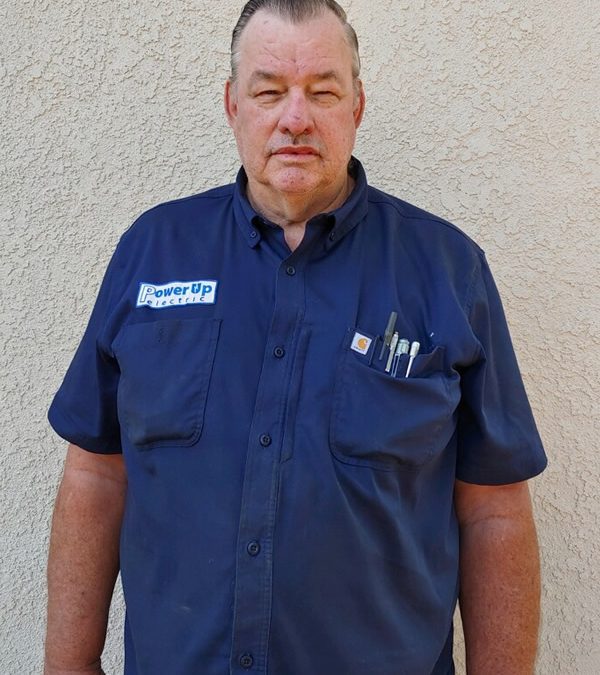 Portrait of a man in a Power Up Electric shirt standing against a textured wall